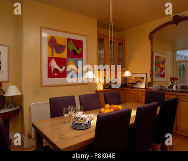 Lampade pensili sopra rettangolare tavolo in legno di colore giallo in sala da pranzo con immagini di grandi dimensioni Foto Stock