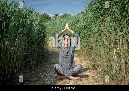 La donna a praticare yoga e meditazione all'aperto in un campo Foto Stock