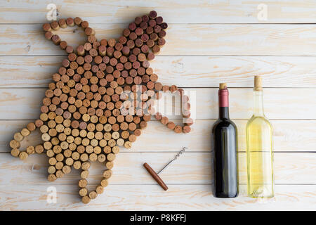 Non etichettati due bottiglie di vino rosso e bianco con cavatappi e la forma della tartaruga marina fatta di utilizzati tappi vino, visto la luce sul tavolo di legno visualizzati Foto Stock