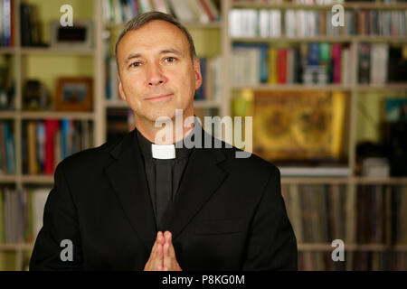 Guardare un buon sacerdote cattolico è pregare nella sua libreria. Egli guarda noi con serenità, di ottimismo, di gioia e di ammirazione, la fiducia, la fiducia e la pace. Foto Stock