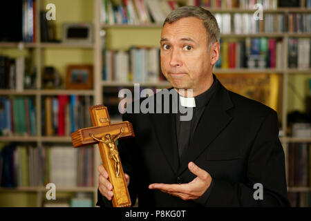 Guardare un buon sacerdote cattolico è che mostra un crocifisso. Egli seriamente ci guardano con interesse, pensiveness e il proselitismo. Foto Stock