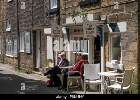 Due persone che sedeva al tavolo esterno cafe in strada a Robin Hood's Bay,Yorkshire Costa Patrimonio,l'Inghilterra,UK Foto Stock