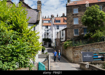 Due persone che camminano per la strada di Robin Hood's Bay,Yorkshire Costa Patrimonio,l'Inghilterra,UK Foto Stock