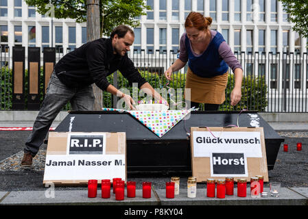 Berlin, Berlin, Germania. 12 Luglio, 2018. Gli attivisti visto posizionando una torta di compleanno per Horst Seehofer su una bara.Gli attivisti protesta di fronte al Ministero Federale degli Interni durante la veglia per il profugo afgano Jamal Nasser M. Il 23-anno-vecchio ha preso la sua vita dopo essere stato espulso dalla Germania in Afghanistan. Ministro federale tedesco dell'Interno, Horst Seehofer fatto scherzi circa questa speciale deportazione durante la presentazione del piano di migrazione. Credito: Markus Heine SOPA/images/ZUMA filo/Alamy Live News Foto Stock