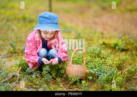 Adorabile ragazza foxberries raccolta nella foresta sul giorno di estate Foto Stock