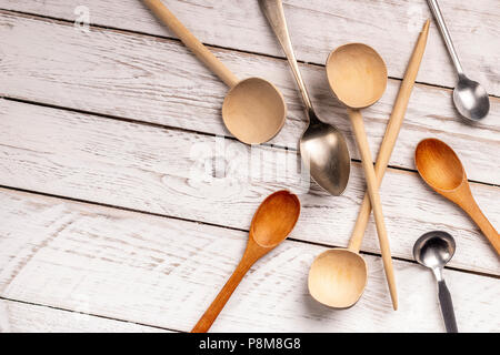 Dal di sopra del legno e metallo per cucchiai di svariate forme giacente sul bianco sullo sfondo di legno Foto Stock