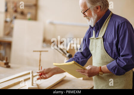 Close-up vista laterale ritratto della vecchia maschio scheda di misura prima della cucitura che nella camera di lavoro Foto Stock
