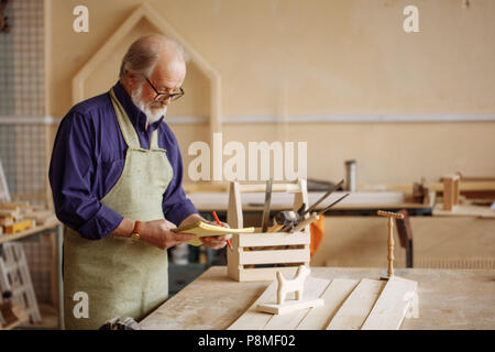 Il vecchio maestro in bicchieri è la creazione di giocattoli per i bambini. closeup vista laterale verticale. copyspace. Foto Stock