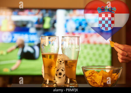 Doppia esposizione della bandiera croata e due bicchieri di birra nella parte anteriore della TV a giocare il gioco del calcio Foto Stock