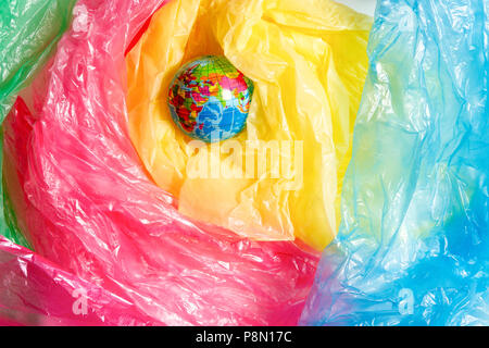 Piccolo globo tra un cumulo di sacchetti di plastica. Plastica uso eccessivo concetto problema Foto Stock