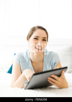 Donna sorridente che tiene la cartella sul letto Foto Stock