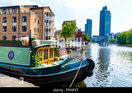 Un accogliente casa galleggiante posto barca sul Regents Canal con lusso grattacieli residenziali in background, London, Regno Unito Foto Stock