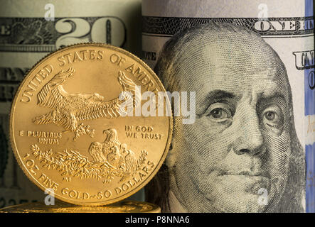Monete d'oro puro davanti a banca di rotoli di valuta statunitense Foto Stock