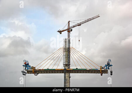 La formatura di ponte strallato procedendo su due lati della centrale alto molo di cemento mediante gru a torre per il terzo ponte sul fiume Mandovi, Goa Foto Stock