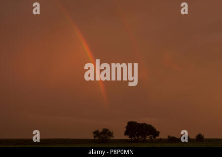 Durante il tramonto il cielo e rainbow girare rosso Foto Stock