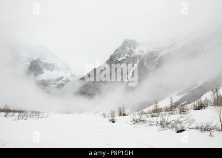 Atmosfera drammatica durante la primavera nelle Alpi francesi con la fusione della neve e nuvole basse pendenti Foto Stock