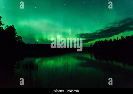 Green Northern lights riflettendo in un lago della Finlandia centrale Foto Stock