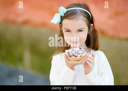 Adorabile bambina di mangiare fresche dolci la torta di fragole all'aperto sul sole e caldo giorno d'estate in Italia Foto Stock