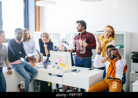 Due pazzi i membri del team stanno prendendo foto stessi mentre i loro collaboratori a discutere di trattativa Foto Stock