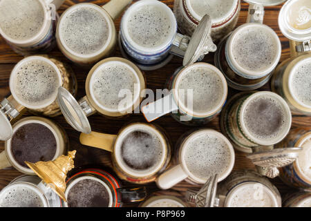 Un assortimento di pieno, spumosi tedesco boccali da birra su un banco bar alto. Foto Stock