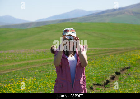 Una donna in un corpetto rosa e un turchese cappello da baseball fotografie montagne Foto Stock