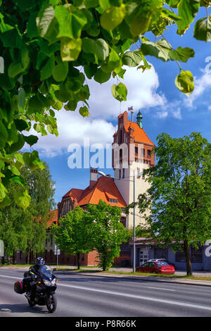 Firehouse edificio in Riga su uno sfondo di verdi alberi e passando sulla strada biker Foto Stock