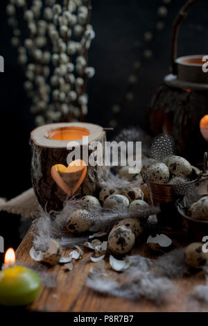 Pollo uova di quaglia, candele e rami di alberi, le piume e le decorazioni per la Pasqua. Spazio di copia Foto Stock