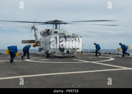 180711-G-ZV557-1011 OCEANO PACIFICO (11 luglio 2018) Coast Guard equipaggio di volo si muovono attraverso il ponte di volo della USCGC Bertholf WMSL (750) Luglio 11, 2018 per fissare un elicottero dal giapponese marittima Forza di Autodifesa destroyer elicottero nave JS Ise (DDH 182) circa 15 miglia a sud-ovest di Oahu, Hawaii, a sostegno di RIMPAC 2018. Venticinque nazioni, più di 46 navi e cinque sommergibili, circa 200 aerei e 25.000 personale partecipano RIMPAC dal 27 giugno al 2 agosto in e intorno all'Isola di Hawaii e la California del Sud. Il più grande del mondo marittimo internazionale exerc Foto Stock