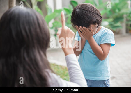 Arrabbiato madre scolding figlia che copre il volto in salotto Foto Stock