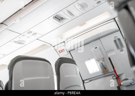 Uscita di emergenza a bordo di un aeromobile, vista dall'interno del piano. Vuoto aereo sedi nella cabina. Moderno concetto di trasporto. Aeromobili a lunga distanza di volo internazionale Foto Stock