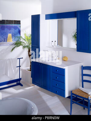 Specchio nel blu armadio montato sopra lavabo bianco in blu+bianco unità vanity in economia bagno in stile dipinto con pianale in legno Foto Stock