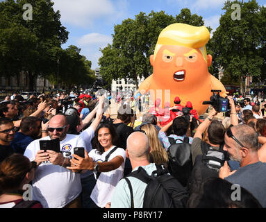 La gente a prendere una 'selfie' come un "Baby Trump' sorge a palloncino dopo essere gonfiata a Londra in piazza del Parlamento, come parte delle proteste contro la visita del Presidente americano Donald Trump AL REGNO UNITO. Foto Stock