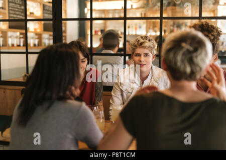 Giovani amici di sesso femminile godendo bevande insieme in un bar alla moda Foto Stock