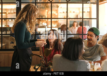 Gruppo sorridente di amici ordinare del cibo in un bistro Foto Stock