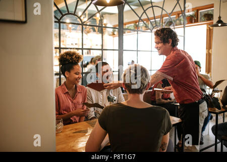 Gruppo di amici sorridente ordinare del cibo da un bistrot cameriere Foto Stock