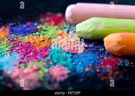 Briciole di multi-colore di gesso su uno sfondo nero. Un gioco per i bambini. Arte Foto Stock