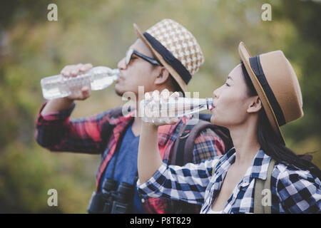 Asian coppia giovane ai viaggiatori di bere acqua su uno sfondo verde, escursionismo concetto, Smiley face. Foto Stock