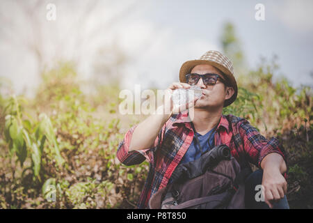 Maschio asiatici ai viaggiatori di bere acqua su uno sfondo verde, escursionismo concetto, Smiley face. Foto Stock