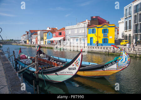 Due Moilceiros colorati (barche originariamente utilizzato per raccogliere le alghe) ormeggiate vicino tradizionali case di pescatori su un canale in Aveiro, Portogallo Foto Stock