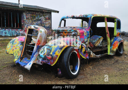 Il guscio di una vecchia auto si siede coperti in colorate spray-dipinto graffiti al di fuori di un abbandonato trading post nel percorso 66 città di Conway, Texas. Foto Stock
