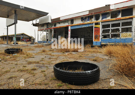 Pneumatici di sedersi di fronte un abbandonato e vandalizzato garage e stazione di gas nel percorso 66 comunità di Conway, Texas, a est di Amarillo. Foto Stock