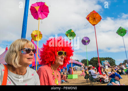 Henham Park, Suffolk, Regno Unito. 13 luglio 2018. Il venerdì e il suo la parrucca arancione - un visitatore ha un colore diverso per ogni giorno! Una scultura di ombrelloni colorati fornisce un punto focale in teh Arena - Il 2018 Latitude Festival, Henham Park. Suffolk 13 luglio 2018 Credit: Guy Bell/Alamy Live News Foto Stock