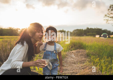 Il Portrait di madre e figlia godendo di giocare con bolla di outdoor in bel tramonto Foto Stock
