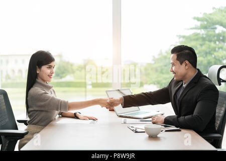 Paio di Asian business persone con abbigliamento casual parlando con felice e agitando la mano in un ufficio moderno o coffee shop. Business il concetto di successo Foto Stock