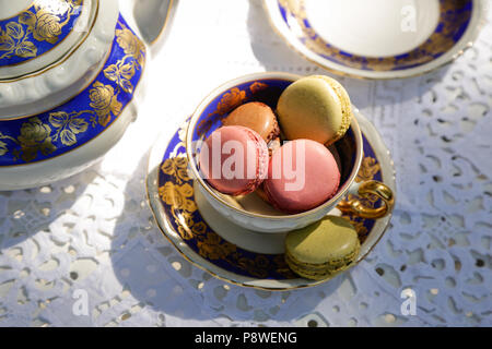 Una tazza di tè con macaron al cioccolato, luce naturale su tavolo in legno Foto Stock