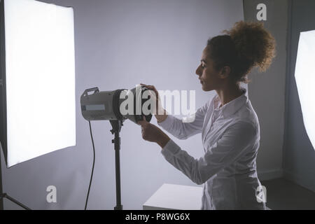 Fotografo femmina regolazione fari stroboscopici Foto Stock