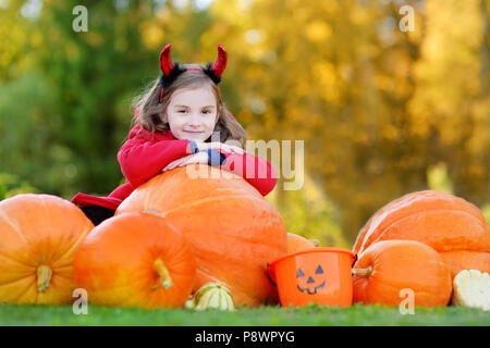 Adorabile bambina indossando il costume di halloween per divertirsi in un orto di zucche Foto Stock