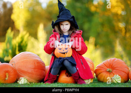 Adorabile bambina indossando il costume di halloween per divertirsi in un orto di zucche Foto Stock