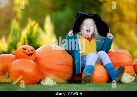 Adorabile bambina indossando il costume di halloween per divertirsi in un orto di zucche Foto Stock