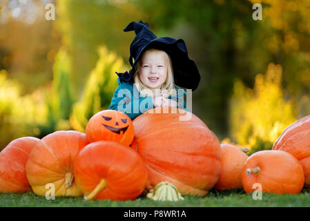 Adorabile bambina indossando il costume di halloween per divertirsi in un orto di zucche Foto Stock